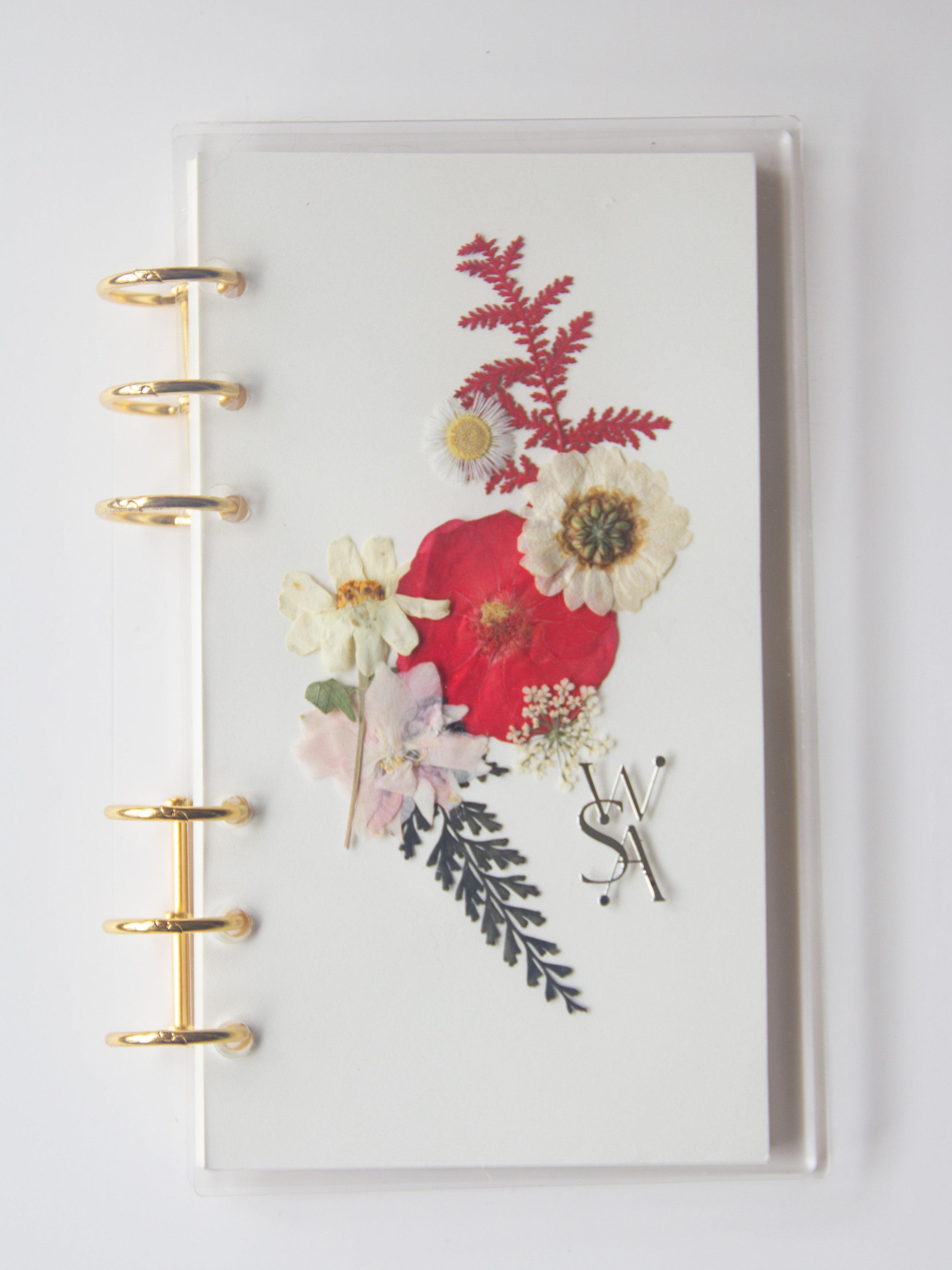 Notebook with floral design and gold rings on a white background